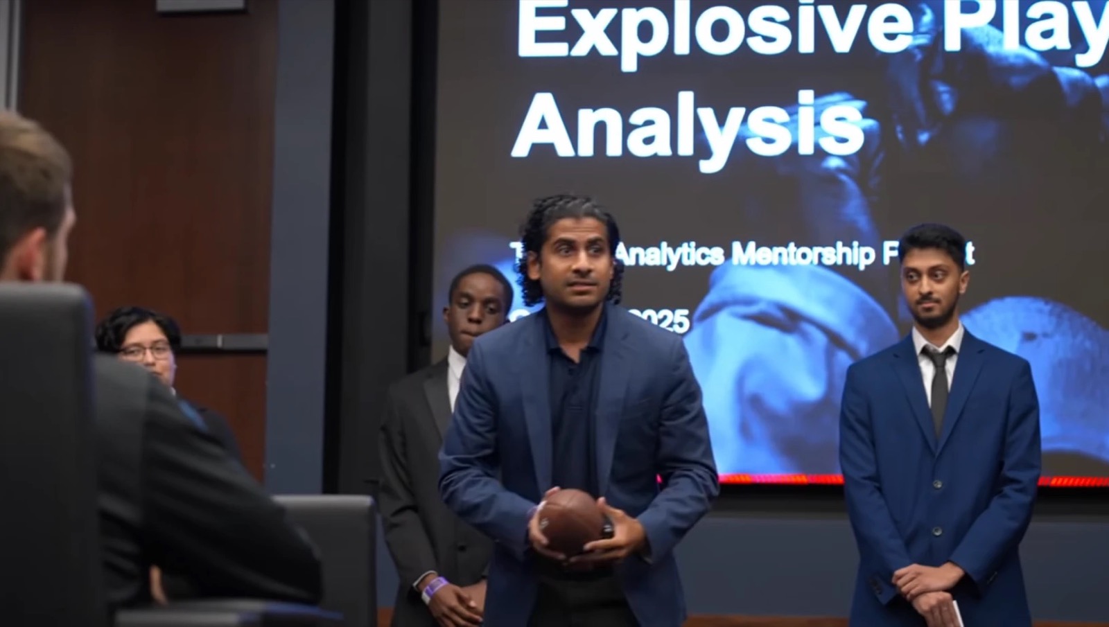 Avi opening the presentation with a football in hand, title slide behind him